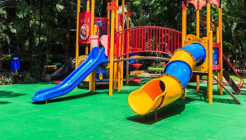 a colorful playground with a slide and a tunnel in a park .