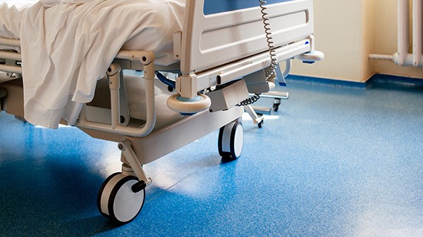 Empty hospital bed on hospital ward in a clean room Epoxy floor in hospital room | All American Flooring